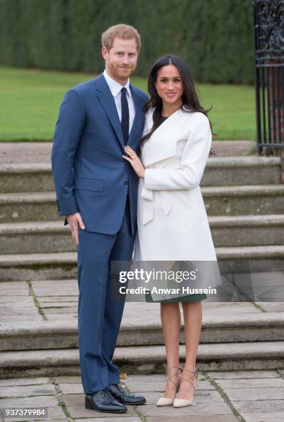 Prince Harry and Meghan Markle, wearing a white belted coat by Canadian brand Line The Label, attend a photocall in the Sunken Gardens at Kensington...