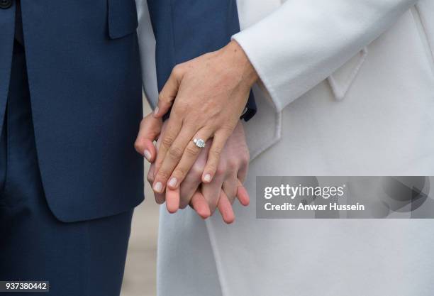 Prince Harry and Meghan Markle, wearing a white belted coat by Canadian brand Line The Label, attend a photocall in the Sunken Gardens at Kensington...