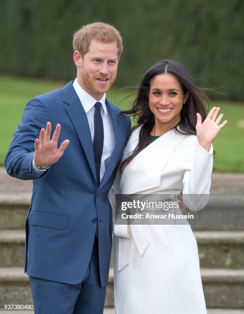 Prince Harry and Meghan Markle, wearing a white belted coat by Canadian brand Line The Label, attend a photocall in the Sunken Gardens at Kensington...