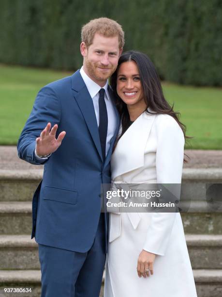 Prince Harry and Meghan Markle, wearing a white belted coat by Canadian brand Line The Label, attend a photocall in the Sunken Gardens at Kensington...