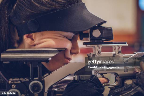young woman practicing at shooting range - sharp shooting stock pictures, royalty-free photos & images