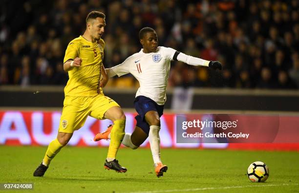 Ademola Lookman of England is tackled by Virgil Ghita of Romania during the International Friendly between England U21 and Romania U21 at Molineux on...