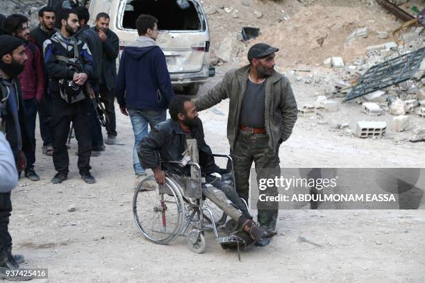 Syrian people walk down a destroyed street as they prepare to evacuate one of the few remaining rebel-held pockets in Arbin, in Eastern Ghouta, on...