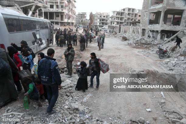 Syrians gather to board busses as they prepare to evacuate one of the few remaining rebel-held pockets in Arbin, in Eastern Ghouta, on the outskirts...