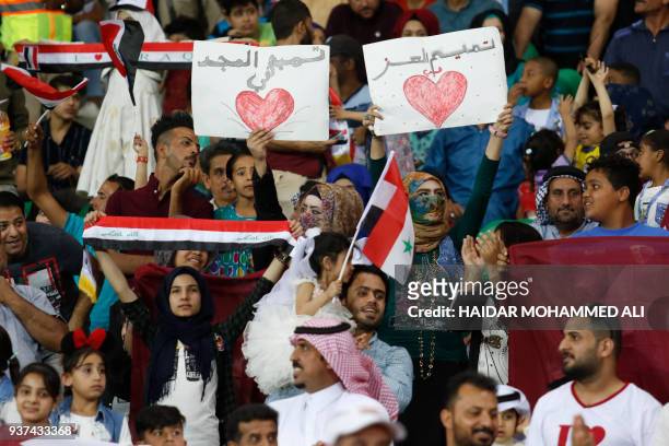 Supporters wave placards reading in Arabic "Tamim in the heart prior to the international friendly football game Qatar vs Syria at Basra Sports City...