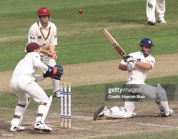 Matthew Mott of Victoria sweeps, with Wade Seccombe and Clinton Perren of Queensland looking on, during day four of the Pura Cup Match between...