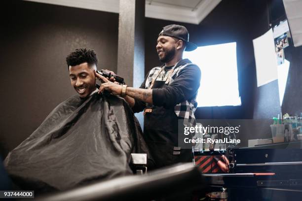 barber giving a haircut in his shop - barber stock pictures, royalty-free photos & images