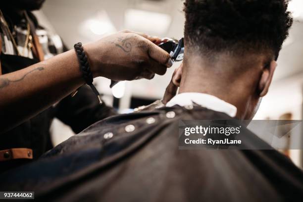 barber giving a haircut in his shop - barbeiro imagens e fotografias de stock