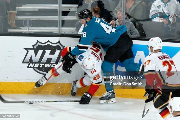 Tomas Hertl of the San Jose Sharks and Nick Shore of the Calgary Flames battle along the boards at SAP Center on March 24, 2018 in San Jose,...