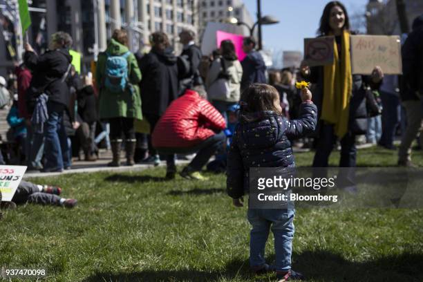 Child holds a flower on Pennsylvania Avenue during the March For Our Lives in Washington, D.C., U.S., on Saturday, March 24, 2018. Thousands of high...