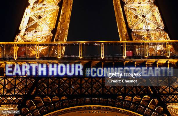 The words "Earth Hour, connect2earth" are projected on the Eiffel Tower before Earth Hour on March 24, 2018 in Paris, France. On the initiative of...