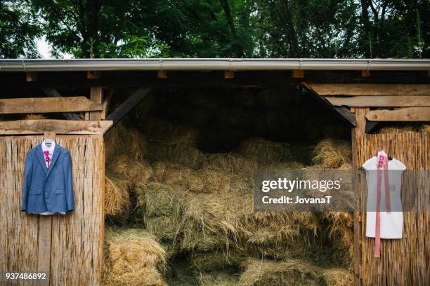 wedding dress and grooms suit hanging on barn with hay - jovanat stock pictures, royalty-free photos & images