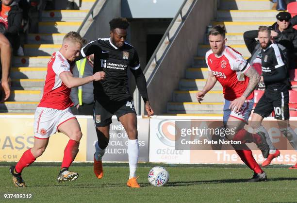 Gboly Ariyibi of Northampton Town moves forward with the ball under pressure from Kyle Dempsey and watched by Ashley Eastham of Fleetwood Town during...