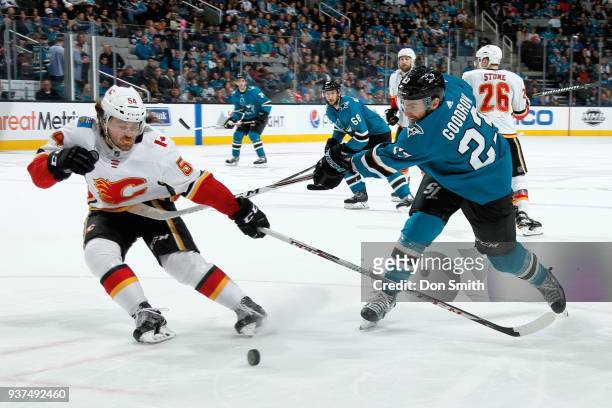 Rasmus Andersson of the Calgary Flames and Barclay Goodrow of the San Jose Sharks battle for the puck at SAP Center on March 24, 2018 in San Jose,...