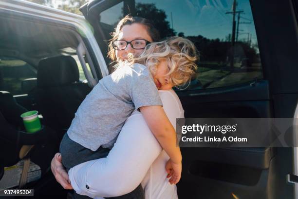 parent removing child from car - auto schlafen stock-fotos und bilder