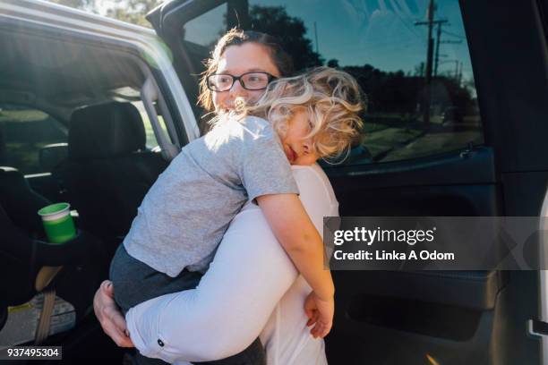 parent removing child from car - sleeping in car foto e immagini stock