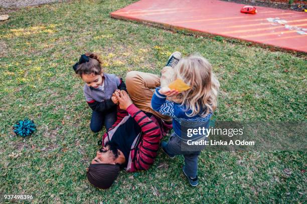 two kids playing with a young adult male outside - louisiana home stock pictures, royalty-free photos & images