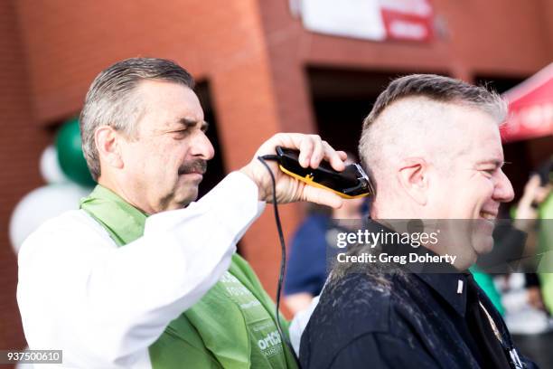 Los Angeles Police Chief Charlie Beck shaves the head of Los Angeles Police Department Lieutenant Greg Doyle at the St. Baldrick's Foundation...