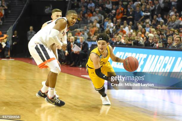 Maura of the UMBC Retrievers dribbles the ball around Devon Hall of the Virginia Cavaliers during the first round of the 2018 NCAA Men's Basketball...