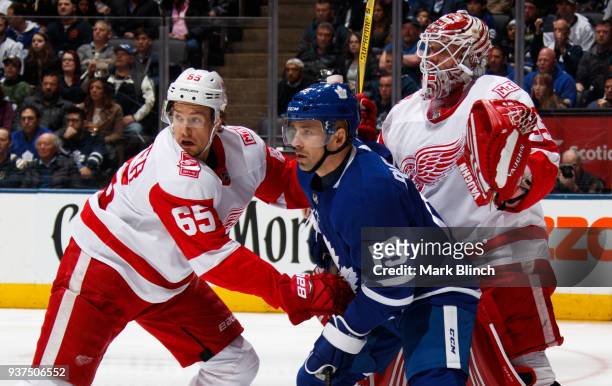 Tomas Plekanec of the Toronto Maple Leafs battles with Danny DeKeyser and Jimmy Howard of the Detroit Red Wings during the first period at the Air...