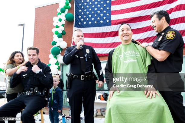 Lieutenant Greg Doyle looks on as Los Angeles Fire Department Chief Ralph Terrazas shaves the head of Los Angeles Fire Department Captain Danny Wu at...