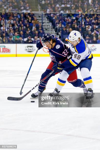 Sonny Milano of the Columbus Blue Jackets and Ivan Barbashev of the St. Louis Blues battle for control of a puck during the first period of the game...