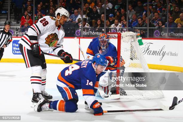 Thomas Hickey of the New York Islanders attempts to block a shot as Andreas Martinsen of the Chicago Blackhawks crashes the net during the second...
