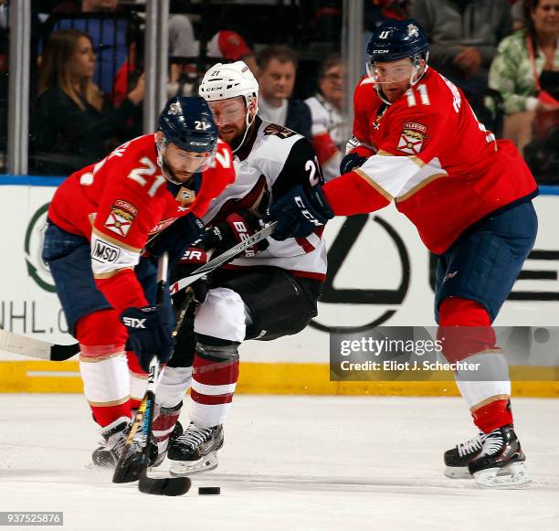 Derek Stepan of the Arizona Coyotes tangles with Vincent Trocheck and teammate Jonathan Huberdeau of the Florida Panthers at the BB&T Center on March...