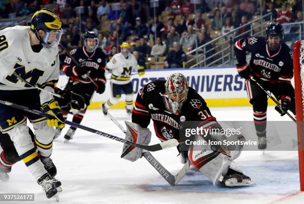 Northeastern goalie Cayden Primeau makes a glove save on Michigan Wolverines forward Dexter Dancs during an NCAA Northeast Regional semifinal between...