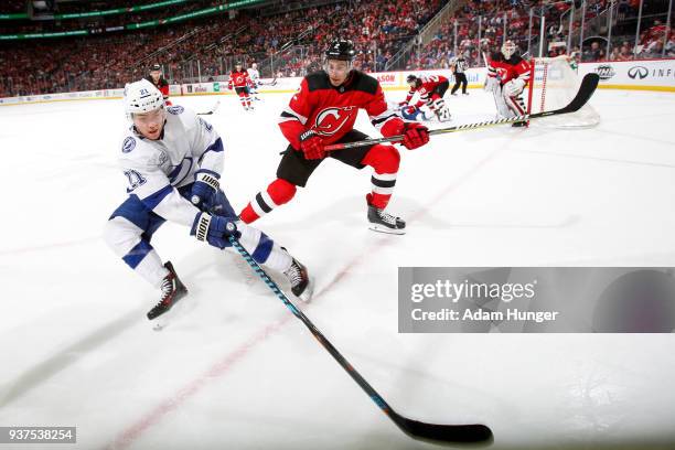 Brayden Point of the Tampa Bay Lightning battles for the puck with John Moore of the New Jersey Devils during the third period at the Prudential...