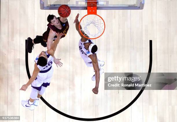 Clayton Custer of the Loyola Ramblers drives to the basket against Mike McGuirl and Xavier Sneed of the Kansas State Wildcats in the second half...