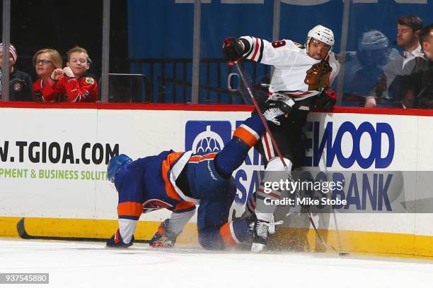 Nick Leddy of the New York Islanders is tripped up by Andreas Martinsen of the Chicago Blackhawks at Barclays Center on March 24, 2018 in New York...