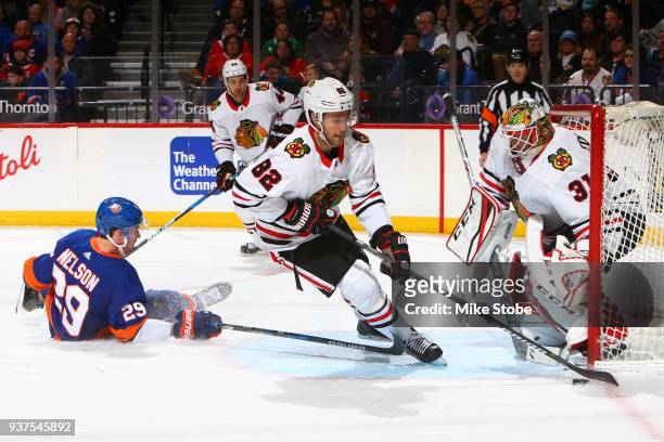 Jordan Oesterle of the Chicago Blackhawks playts the puck as Brock Nelson of the New York Islanders falls to the ice at Barclays Center on March 24,...