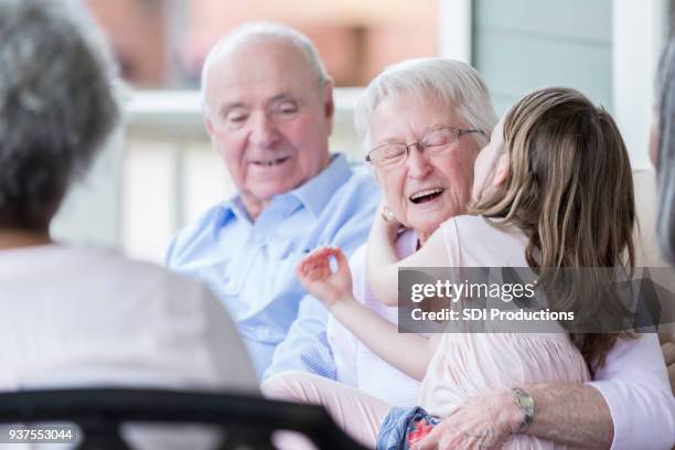 grootmoeder ontvangt kus van jonge kleindochter - friends kissing cheeks stockfoto's en -beelden