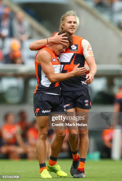Zac Langdon of the Giants is congratulated by team mate Harrison Himmelberg after kicking is his first goal on debut during the round one AFL match...