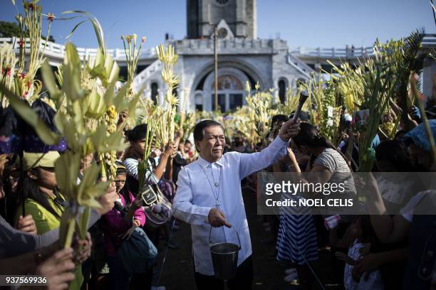 Layman of the Roman Catholic Church blesses palms during Palm Sunday celebrations at the Our Lady of Lourdes Grotto church in Bulacan, north of...