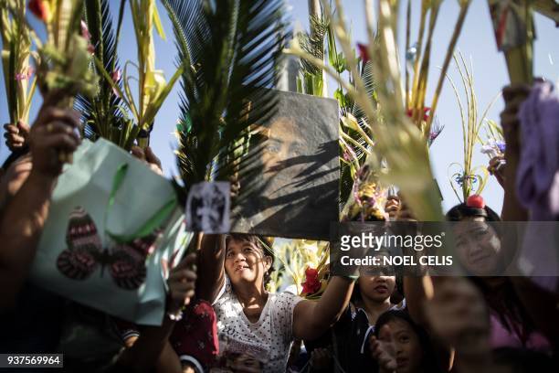 Devotees hold palm fronds as a layman of the Roman Catholic Church blesses palms during Palm Sunday celebrations at the Our Lady of Lourdes Grotto...