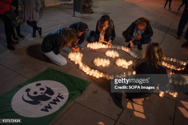 Members from the World Wildlife Fund seen lighting candles during the Earth Hour in downtown Malaga. The figure with candles depicts a panda, the...