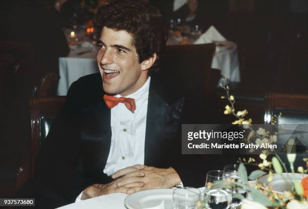 Smiling John F Kennedy, Jr wears a red bow tie at a fundraising event.