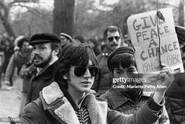 New York, New York Young man holds a sign saying 'Give Peace a Chance 1940-1980' as people commemorate John Lennon in Central Park in New York after...