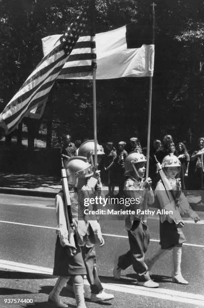 New York, New York - Tuesday, June 11, 1981: Children wear helmets and carry prop guns, American and christian flags as they pass a group of Girl...