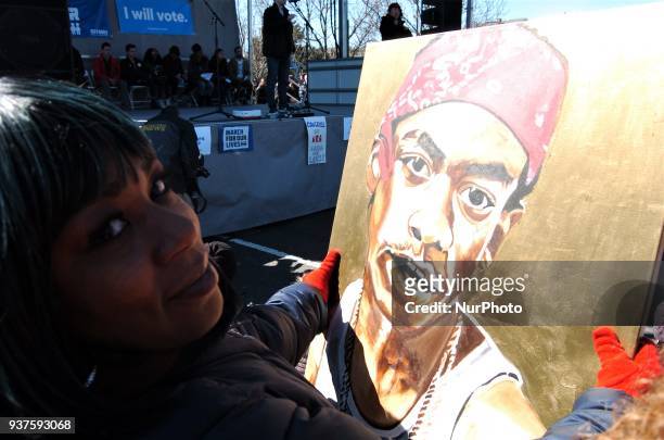 Mother who lost her son to gun violence holds a painting of her son at the stage where students and leaders are speaking during March for Our Lives...