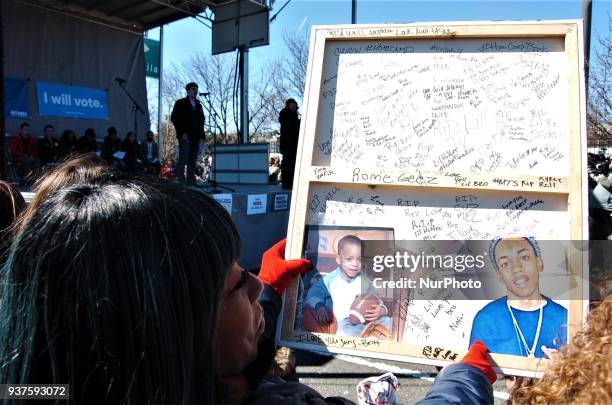 Mother who lost her son to gun violence holds a painting of her son with signatures from his friends and neighbors at the stage where students and...