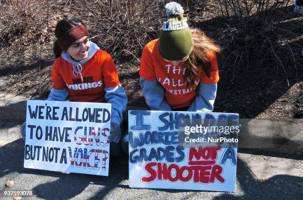 Two high school students take a break with their signs on a curb along the path of the protest during March for Our Lives in Philadelphia on March...