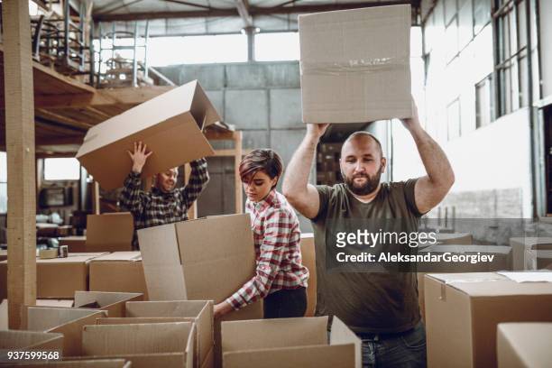 mitarbeiter verpackung ihrer produkte für den versand in ihrer werkstatt - halb mann halb frau stock-fotos und bilder