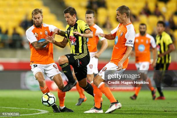 Nathan Burns of the Phoenix breaks through the defence of Jacob Pepper and Thomas Kristensen of the Roar during the round 24 A-League match between...