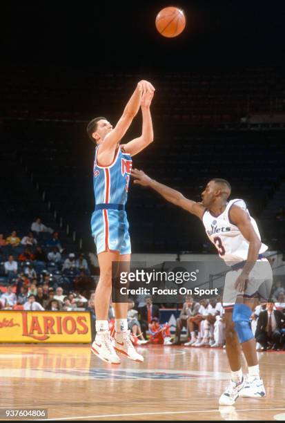 Drazen Petrovic of the New Jersey Nets shoots over Haywoode Workman of the Washington Bullets during an NBA basketball game circa 1991 at the Capital...