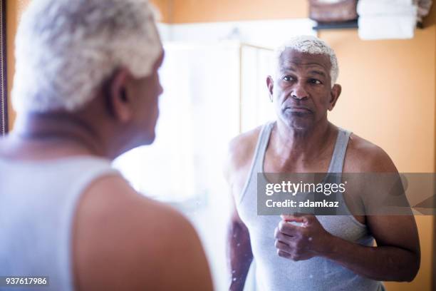 senior black man getting ready in the bathroom - midlife crisis stock pictures, royalty-free photos & images
