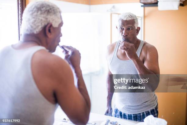 senior black man bushing teeth - people brushing their teeth stock pictures, royalty-free photos & images