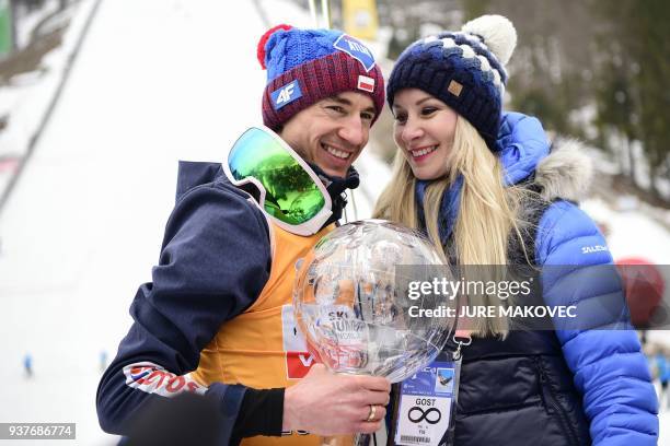 Kamil Stoch of Poland holds the crystal globe trophy as he poses with his wife Ewa Bilan Stoch after he won the overall FIS Ski Jumping World Cup in...